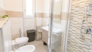 A modern bathroom with a glass shower enclosure, a toilet, a sink, and a bidet. - Appartamento Cittadella (Florence)