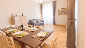 A dining area with a wooden table set for four, a sofa, and a cabinet in the background. - Appartamento Cittadella (Florence)