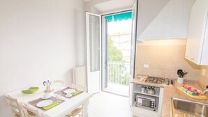A compact kitchen with a dining area, a gas stove, a microwave, and a small sink. - Appartamento Cittadella (Florence)