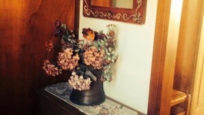 A wooden cabinet with a vase of flowers and a mirror above it. - Al Ponte B&B (Padova)
