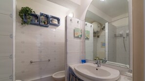 Une salle de bain équipée de toilettes, d’un bidet et d’un grand miroir au-dessus du lavabo.