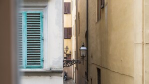Une ruelle étroite, bordée de bâtiments des deux côtés, avec un chemin pavé et un lampadaire.