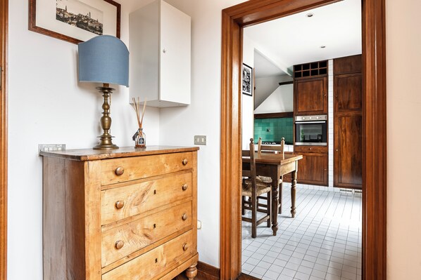 A wooden dresser with drawers, a lamp, and a framed picture on the wall. - Appartamento Portinari (Florence)