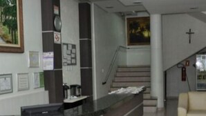 Un área de recepción con un escritorio, certificados enmarcados, una escalera y una cruz en la pared.