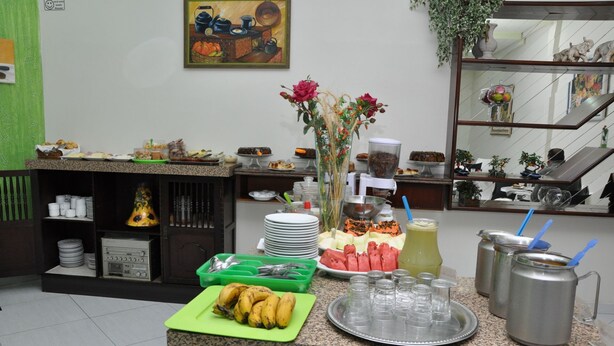 Montaje de bufé con diversas opciones de comida, una tabla de cortar verde con plátanos y un florero decorativo con flores.
