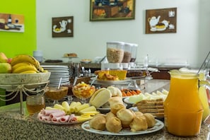 Un buffet de petit-déjeuner proposant divers plats et une carafe de jus d’orange.