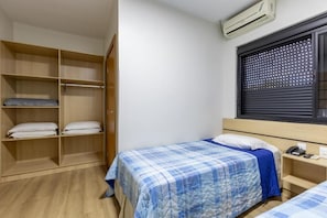 Une chambre à coucher comprenant un lit, une armoire, une fenêtre avec des stores et un appareil de climatisation.