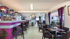 A restaurant with a bar area, multiple tables and chairs, and a view of the outside through large windows. - Joseph Charles (L'Île-Rousse)