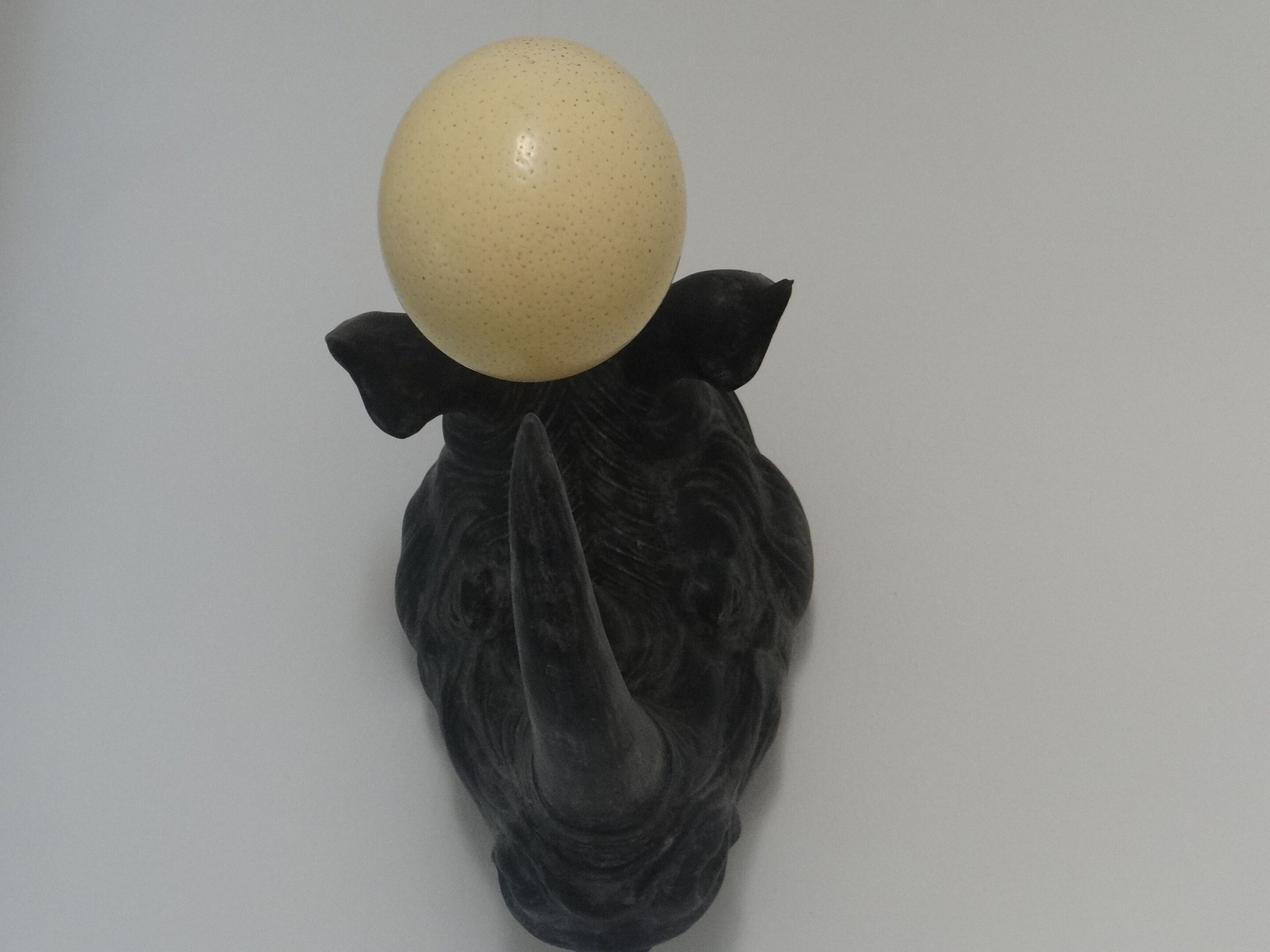 A sculpture of a figure with a spherical head and a feather-like tail.
