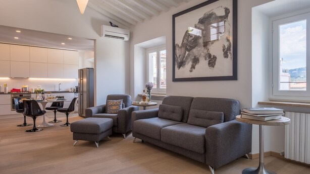 A modern living room with a grey sofa, a small round table, and a large abstract painting on the wall. - Appartamento Matteotti (Florence)