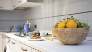 A kitchen counter with a wooden bowl containing oranges and grapes. - Apollonia Apartment (Florence)