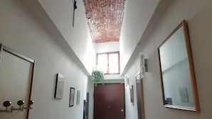 A narrow hallway with a brick ceiling, a wooden door at the end, and a window at the far end. - Appartamento Ruote (Florence)