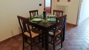 A dining area with a wooden table set for four, surrounded by chairs. - Appartamento Ruote (Florence)