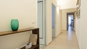 Ein Flur mit einem Holzkonsolentisch, einer grünen Vase und einem Bücherregal.