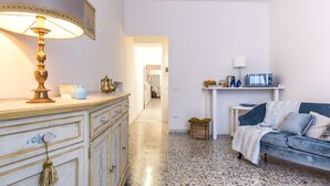 Ein Wohnzimmer mit Sofa, Lampe, Schrank und einem Küchenbereich im Hintergrund.