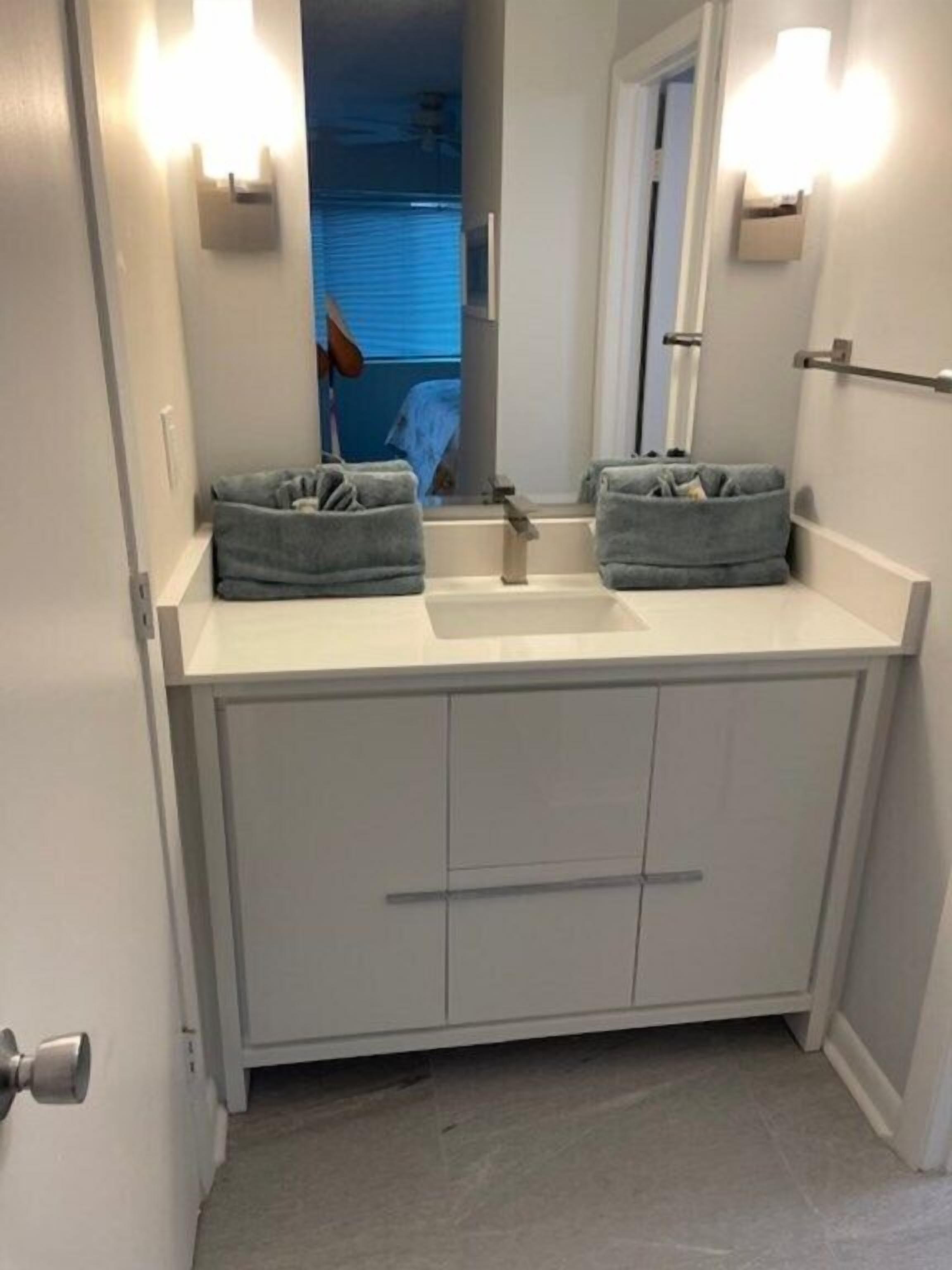 A bathroom with a white vanity, two towel racks, a mirror, and a sink.