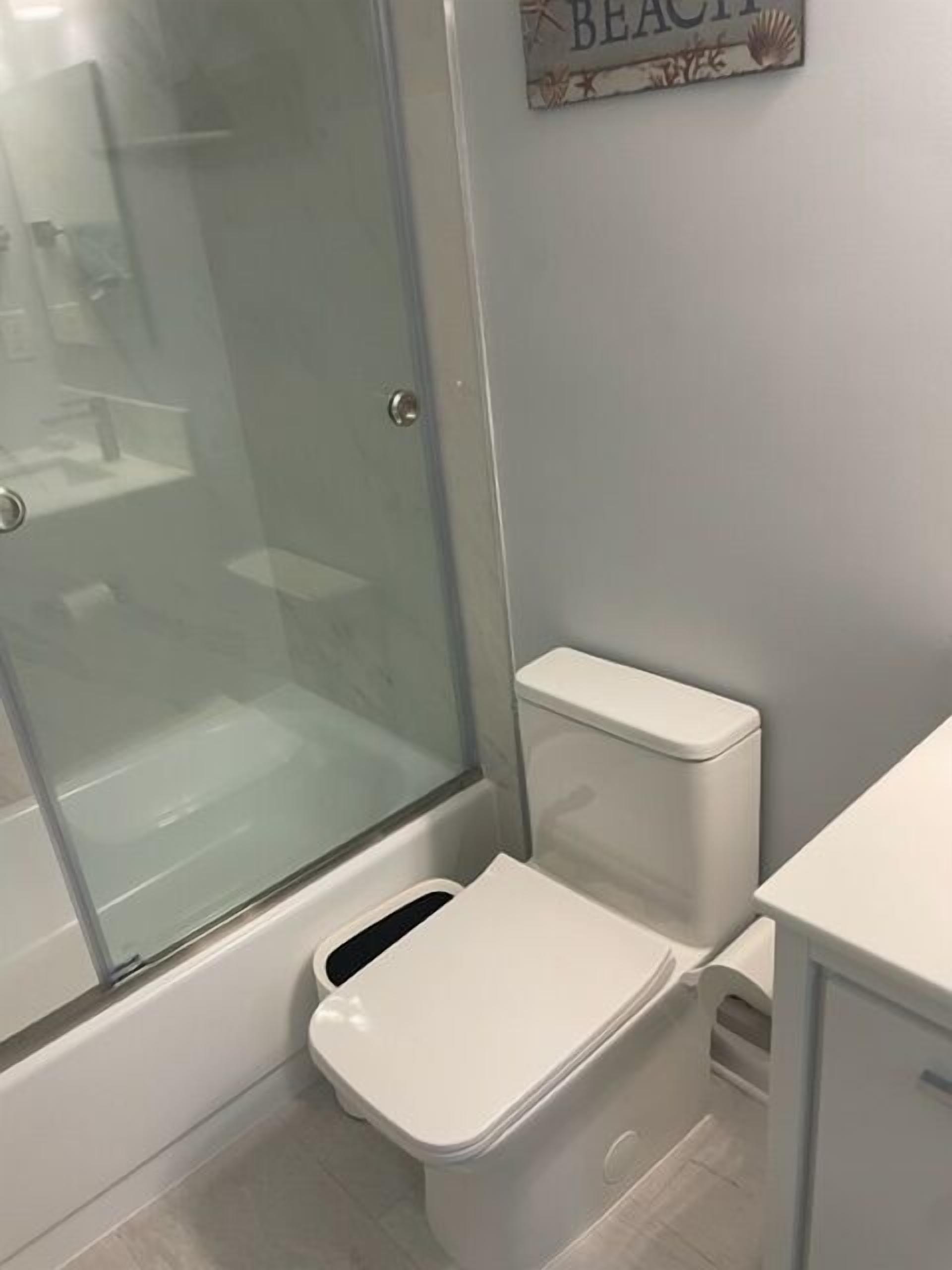 A bathroom with a glass shower enclosure, a toilet, and a sink.