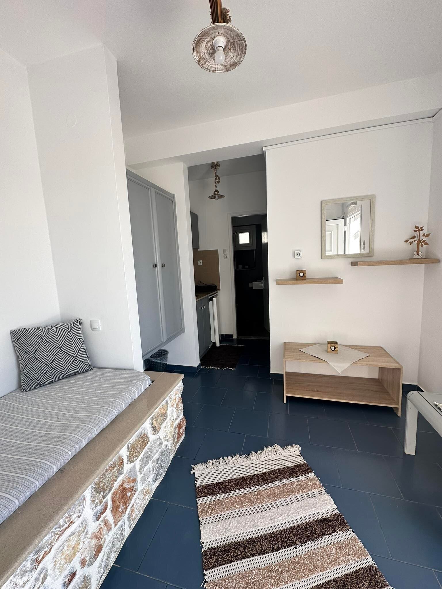 Un soggiorno moderno con una parete in pietra a contrasto, un tappeto a righe, una panca in legno e un lampadario.