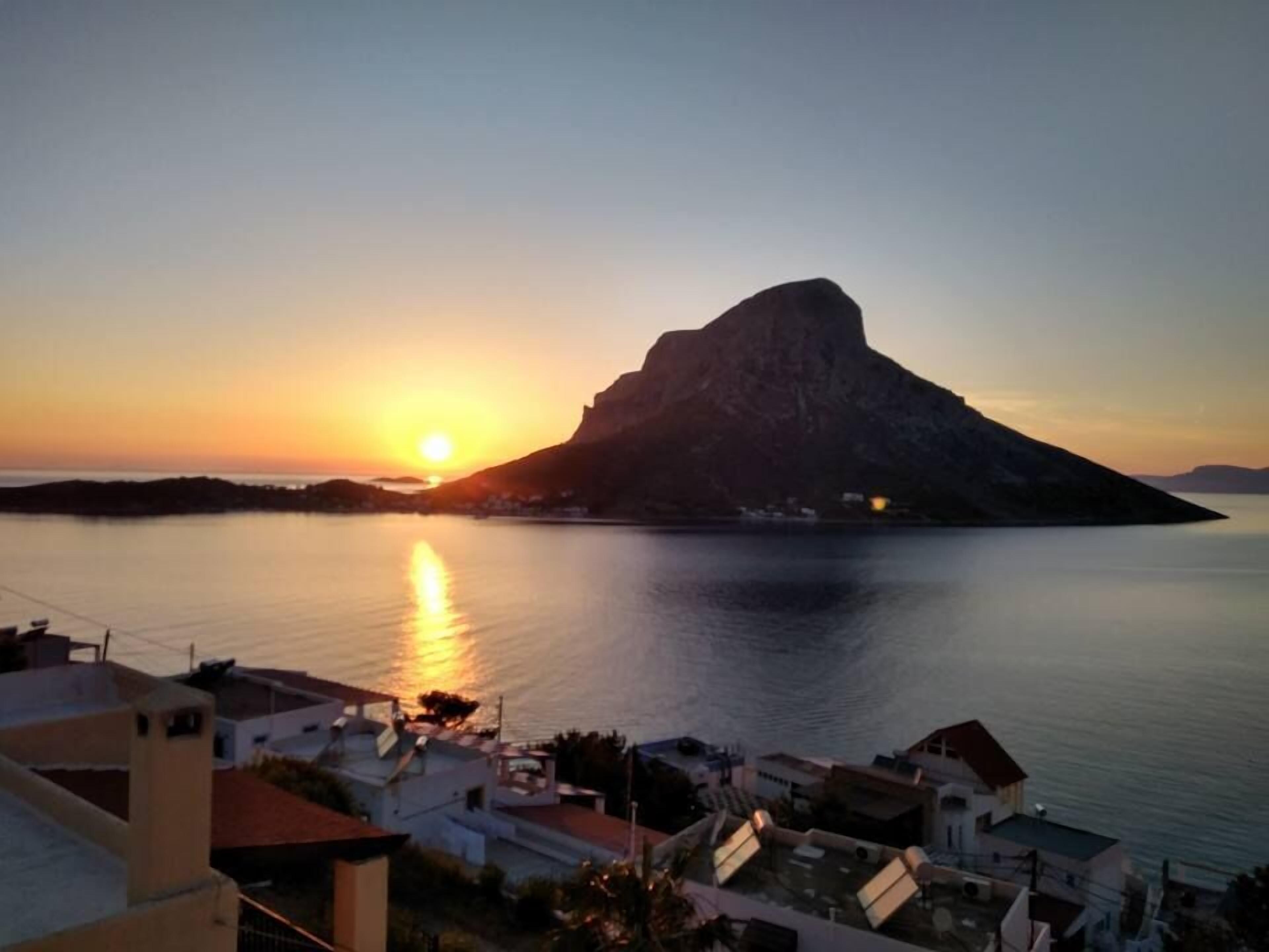 Een kustplaatsje bij zonsondergang, met een opvallende berg op de achtergrond.
