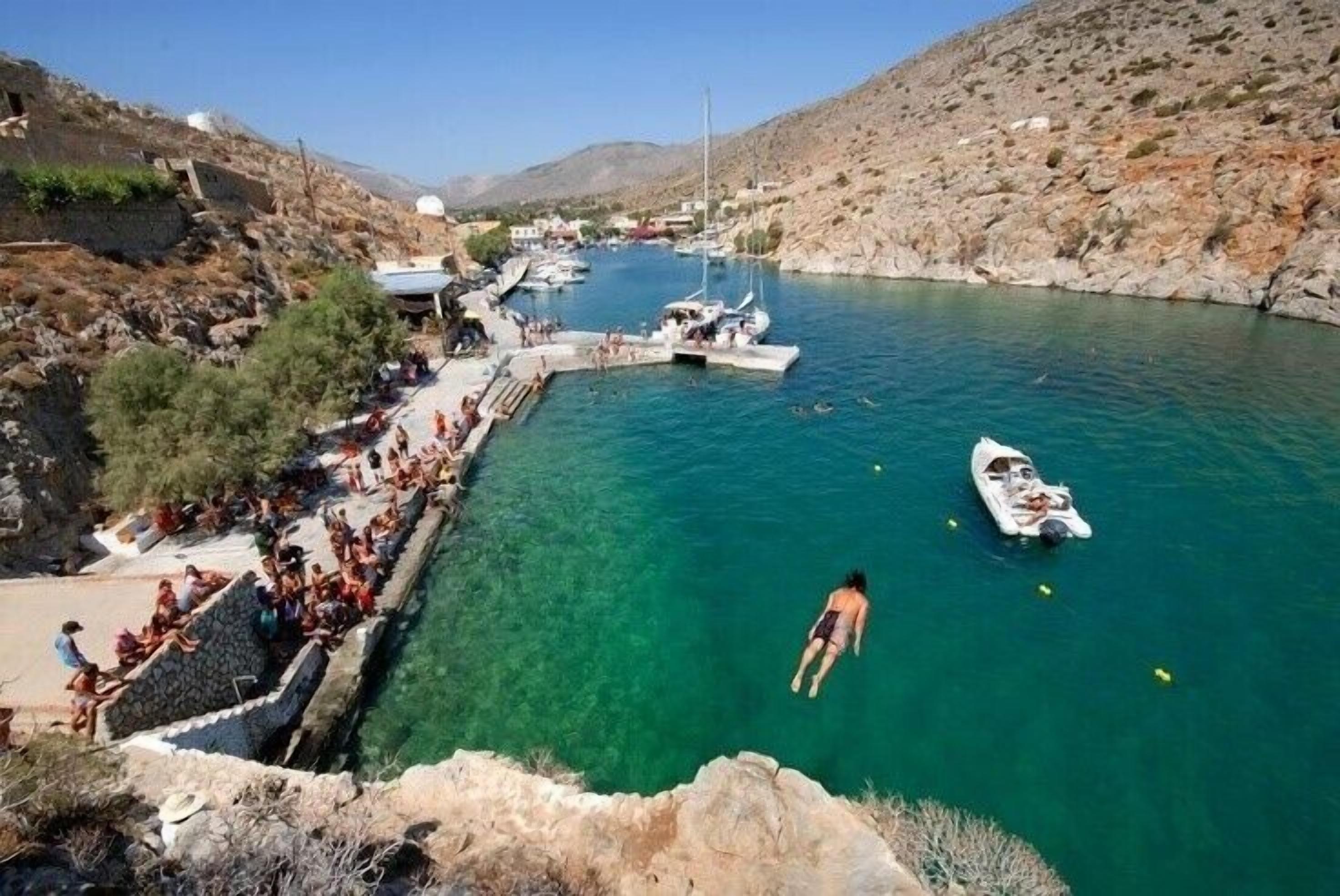 A coastal area with clear water, boats, and a rocky landscape.