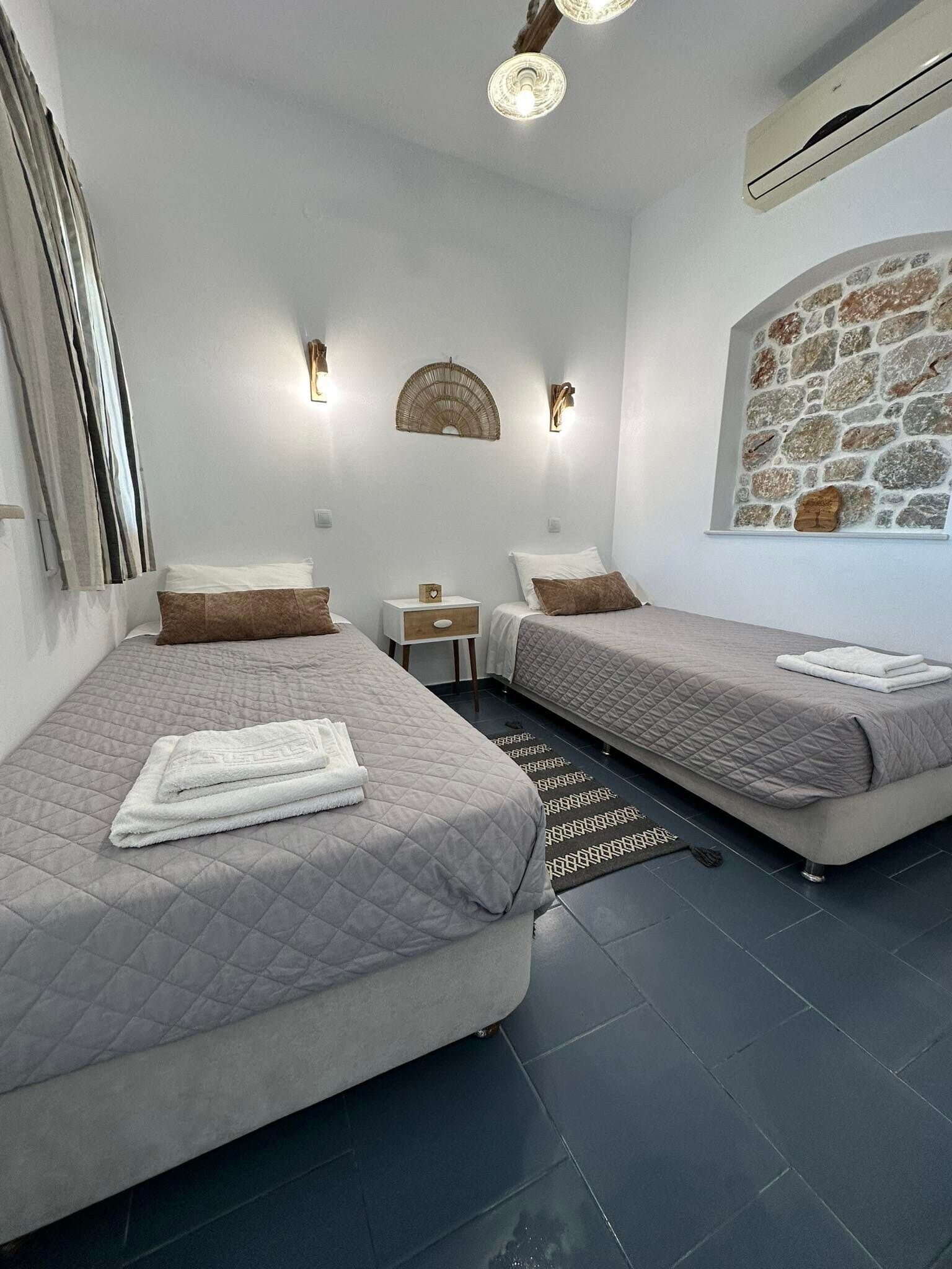 Een hotelkamer met twee bedden, een stenen muur en een plafondventilator.