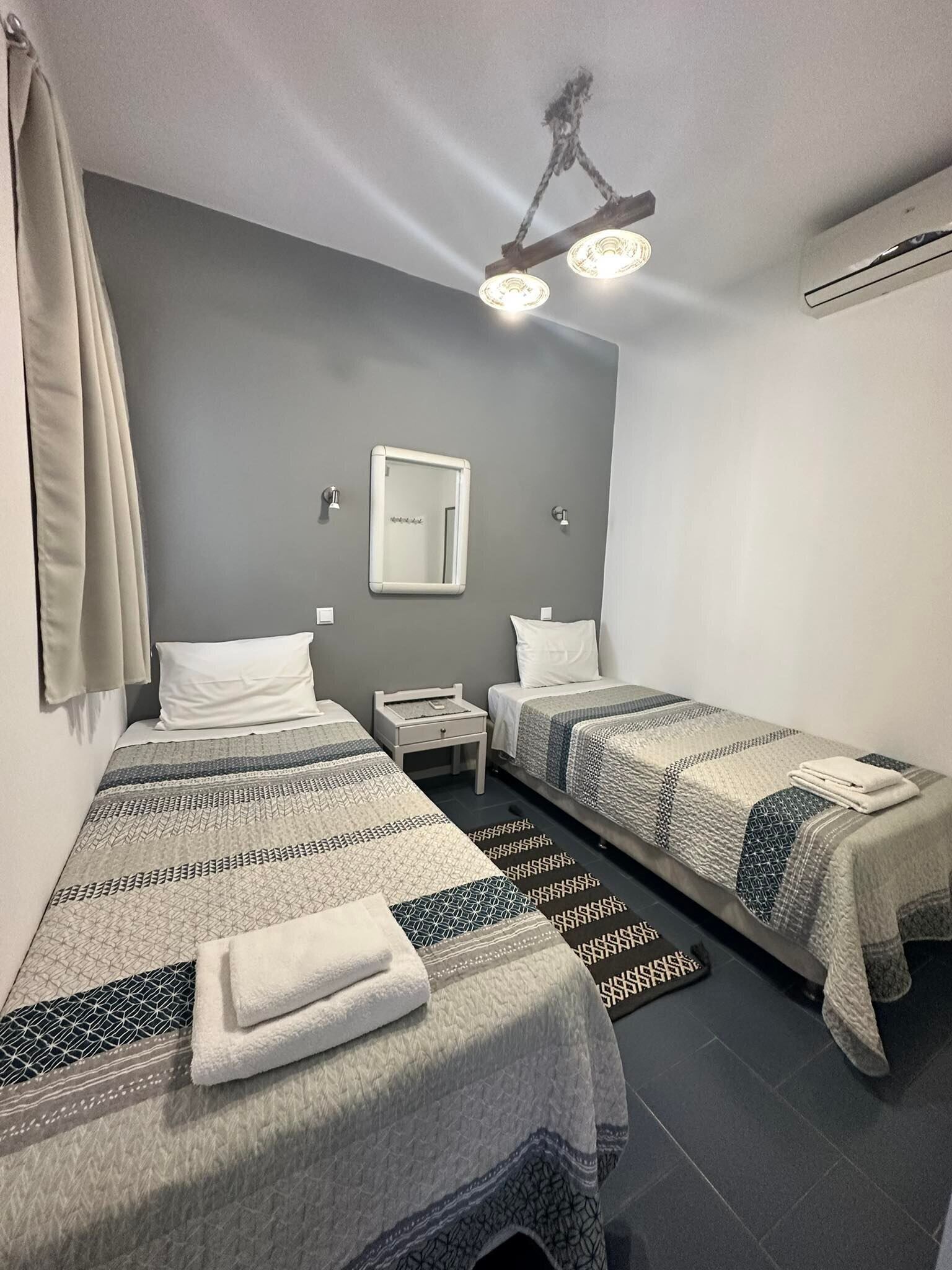 Ein Hotelzimmer mit zwei Betten, einem Nachttisch, einem Spiegel und einer Deckenleuchte.