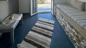 Un dormitorio moderno con un ventanal grande, una cama, un banco y una lámpara de techo.