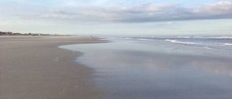 A wide, sandy beach with gentle waves.