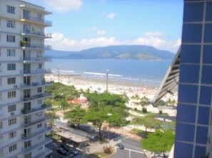 Un edificio a più piani con balconi che si affacciano su una spiaggia e una montagna.