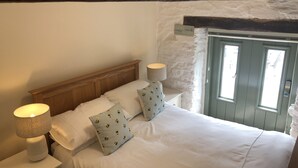 A bedroom with a wooden headboard, white bedding, and two bedside lamps. - Four bedroom stone barn conversion near Dartmoor and Devon beaches (Newton Abbot)