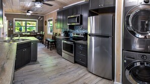 A modern kitchen with stainless steel appliances, wooden flooring, and a view of the outdoors. - Cozy Cove/Beach/FREE Golf Cart/Umbrella/Chairs/Kayak/Quiet Dead End Street (Spanish Wells)