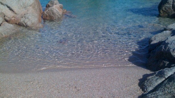 Una playa rocosa con aguas claras y poco profundas.
