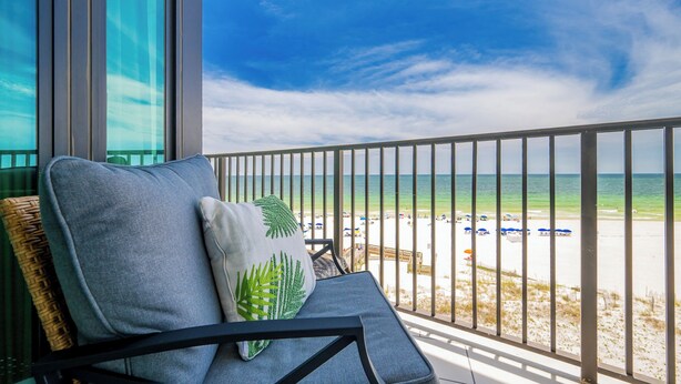 Een balkon met uitzicht op strand en zee.