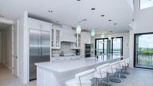 A modern kitchen with a large island, stainless steel appliances, and pendant lighting. - Bayfront Luxury Home with Private Pool, Spa & Panoramic Views (Captiva)