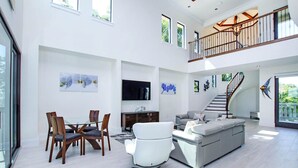 A spacious living area with a dining set, a sofa, and a TV. - Bayfront Luxury Home with Private Pool, Spa & Panoramic Views (Captiva)