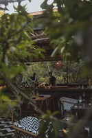 An outdoor dining area with tables and chairs, a person standing near the tables, and a hanging light fixture.