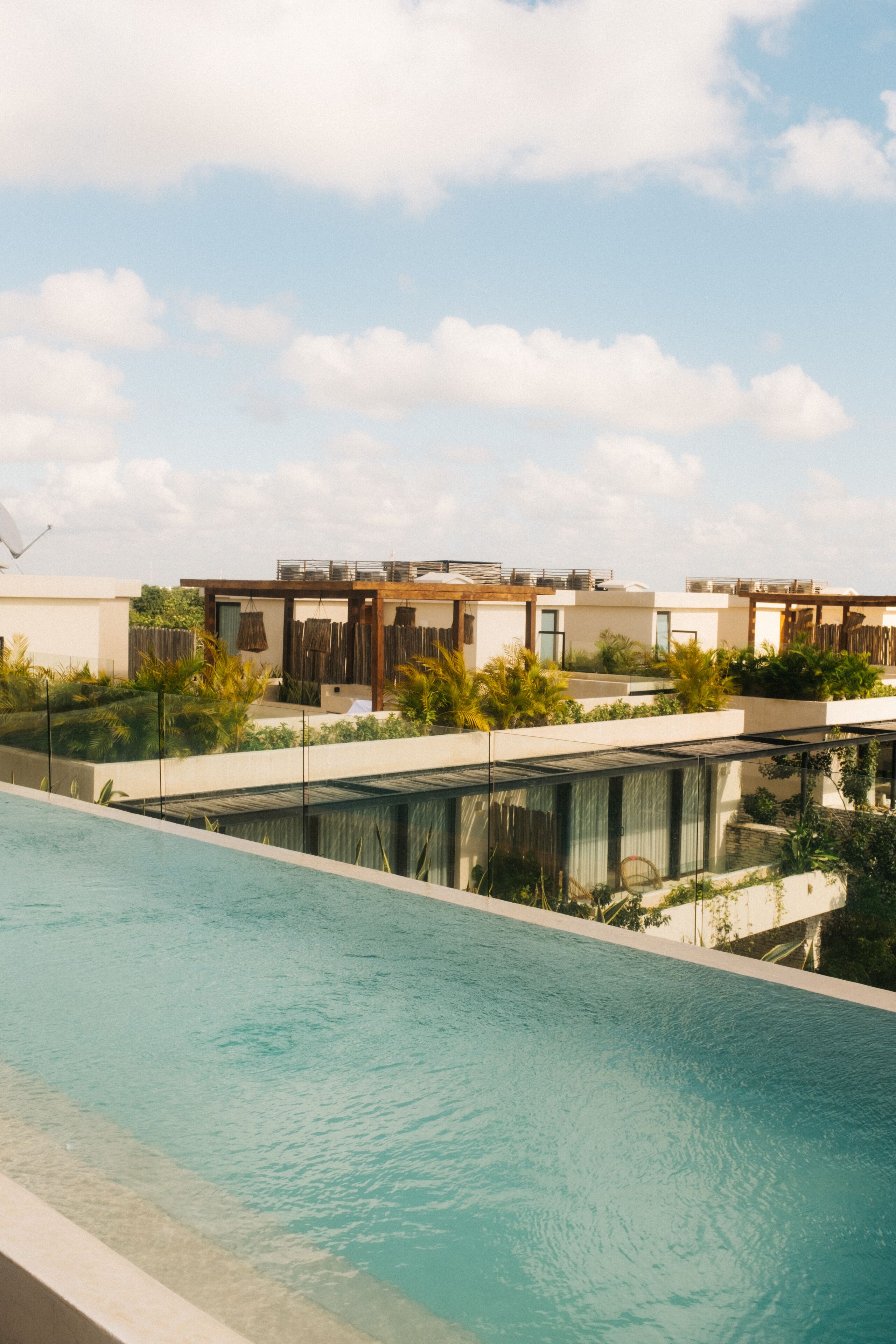 A modern pool area with a clear view of the sky and a row of contemporary buildings in the background.