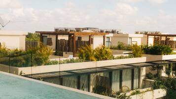 A modern pool area with a clear view of the sky and a row of contemporary buildings in the background.