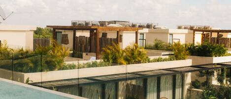 A modern pool area with a clear view of the sky and a row of contemporary buildings in the background.