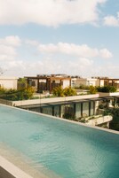 A modern pool area with a clear view of the sky and a row of contemporary buildings in the background.