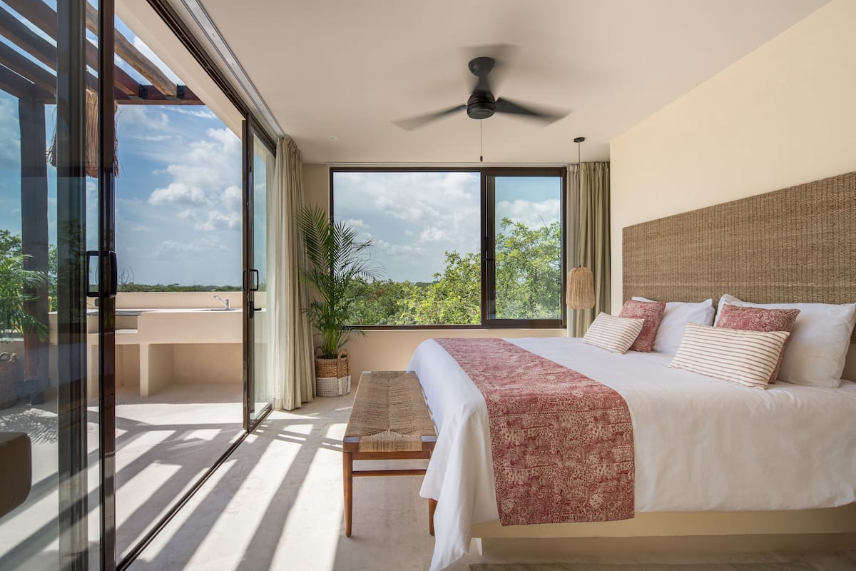 A spacious bedroom with a large bed, a ceiling fan, and a view of the outdoors.