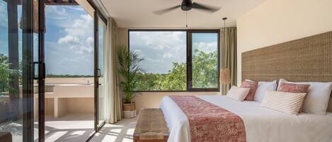 A spacious bedroom with a large bed, a ceiling fan, and a view of the outdoors.