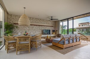 Una sala de estar moderna con pared de piedra, muebles de mimbre, un televisor de pantalla plana y un ventanal con vistas a la ciudad.