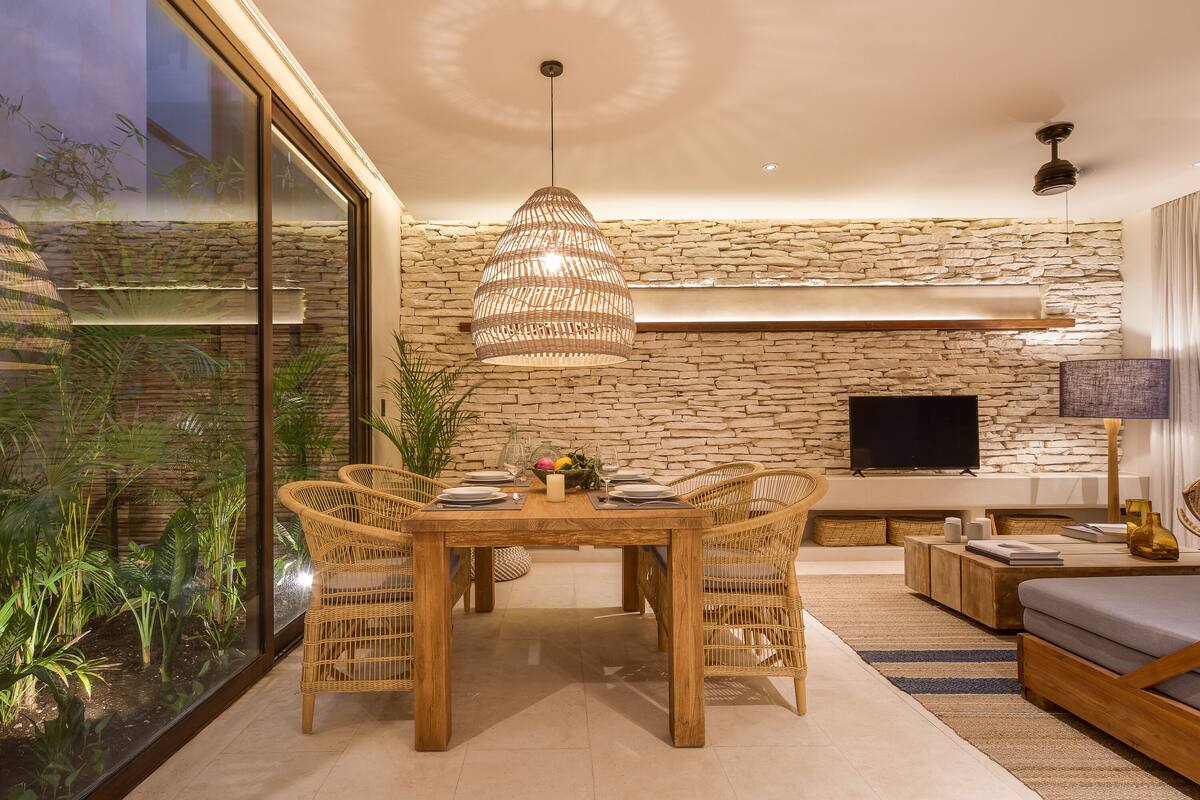A modern dining area with a wooden table, wicker chairs, and a large pendant light.