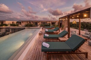 Uma área de piscina no terraço com espreguiçadeiras e um pergolado com luzes de corda.