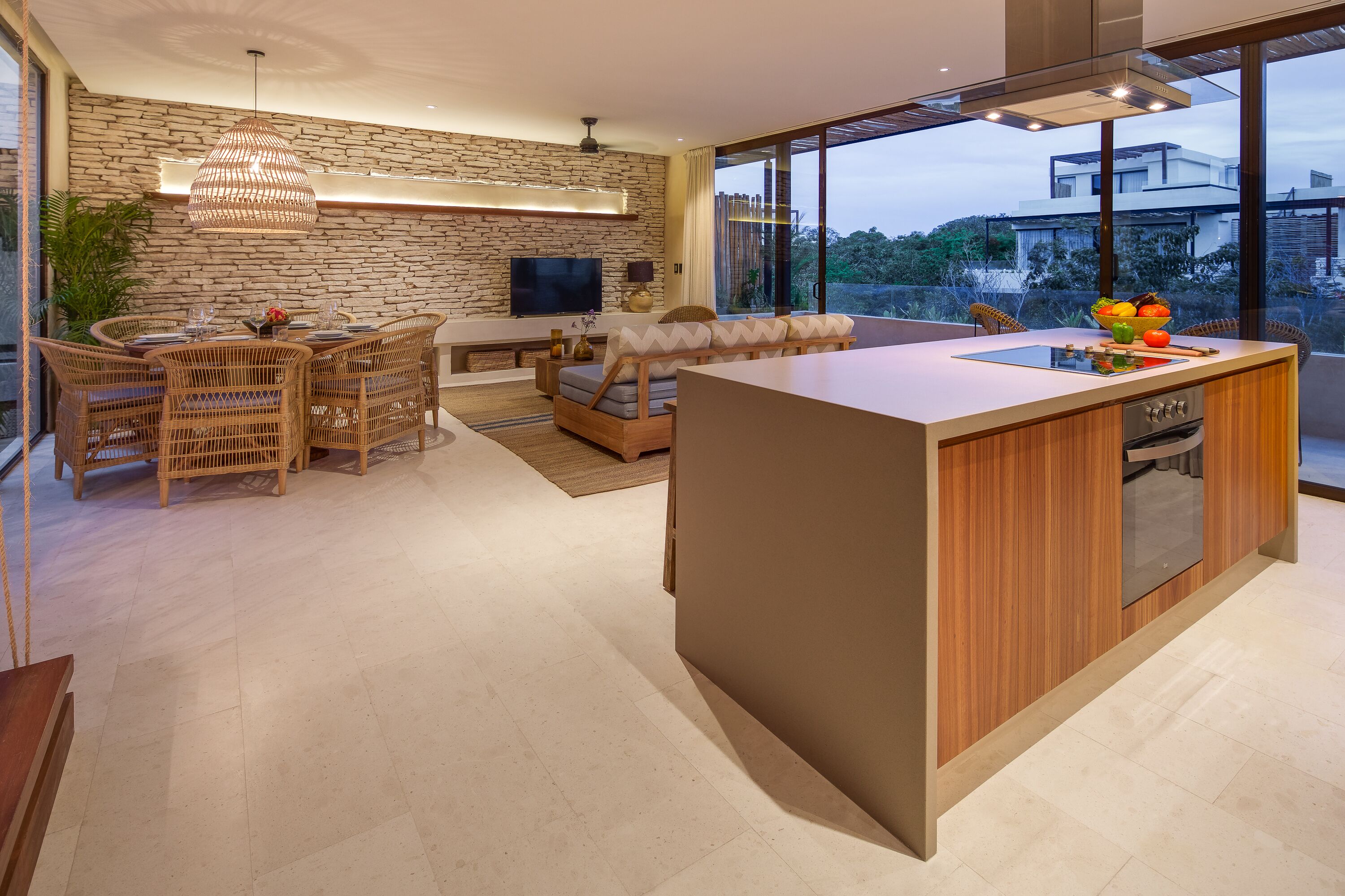 A modern living space with a stone wall, a dining area, and a kitchen island.