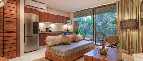 Una sala moderna con sofá, mesa de centro y una zona de cocina con refrigerador y microondas.