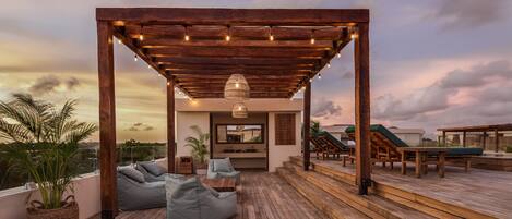 A wooden deck with a pergola, seating area, and outdoor lounge chairs.