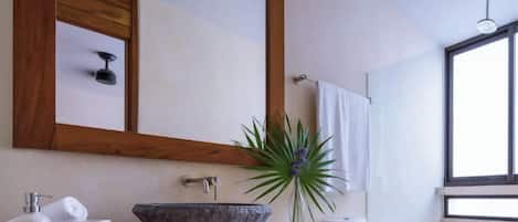 A modern bathroom with a large mirror, a vessel sink, and a toilet.