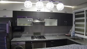 Eine moderne Küche mit Granit Arbeitsplatten, Edelstahlgeräten und Pendelleuchten.